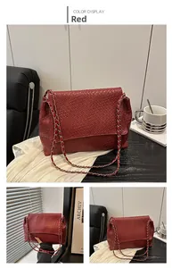 Gros plan d'un sac à bandoulière en cuir tressé rouge foncé avec chaîne en métal doré
