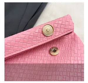 Macro shot of magnetic clasp on pink woven texture PU leather envelope clutch bag