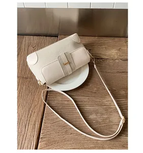 Detail of a beige patchwork shoulder bag with woven texture on a wooden table