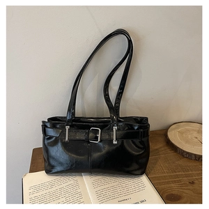 Detail of black glossy leather underarm bag with silver buckle and vintage design