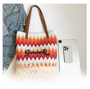 Detail of woven straw tote bag featuring Summer embroidery and brown leather straps