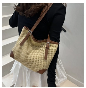 Detail of beige straw tote bag with brown leather straps and adjustable metal buckles
