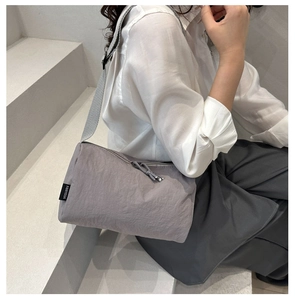 Detailed shot of large grey nylon crossbody bag with fabric strap on model