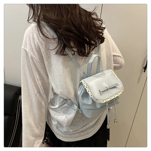 Détail du mini sac à dos bleu clair avec bordure en dentelle, nœud en cuir et cordon serrage
