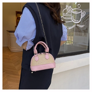 Mini pink and beige straw shell bag with metal chain shown on model in a cafe setting