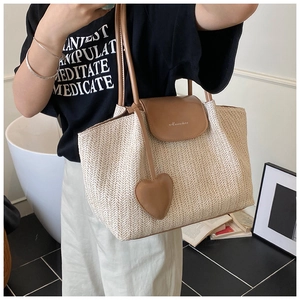 Detailed straw tote bag texture with brown leather accents and heart charm detail