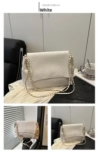 Détail d'un sac à bandoulière blanc à texture tressée avec chaîne dorée sur un bureau