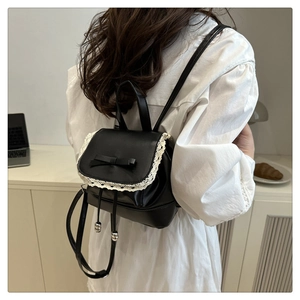 Détail d'un sac à dos en cuir noir avec bordure en dentelle blanche et nœud