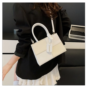 Detail of cream structured crossbody bag with stitched panels and a leather fashion tag