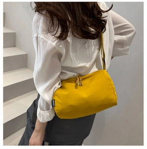 Detail of a bright yellow nylon tote bag featuring a black logo label and knot zipper pull