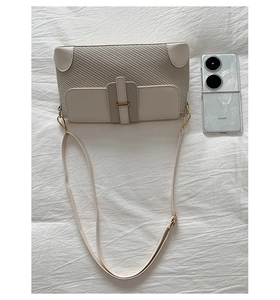 Detail view of small square crossbody bag with beige leather and brown woven texture