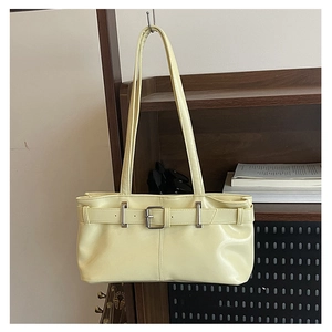 Close-up of cream yellow faux leather underarm bag with decorative belt buckle detail