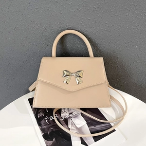 Borsa beige con chiusura a fiocco dorato mostrata frontalmente su base bianca