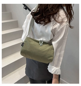 Detail view of the grass green nylon pillow bag featuring a woven brand tag and drawstring