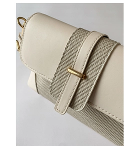 Detailed view of cream leather shoulder bag with textured weave and gold buckle