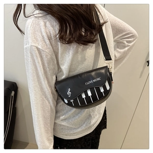 Gros plan du motif clavier de piano et texte I LOVE MUSIC sur sac besace noir rétro