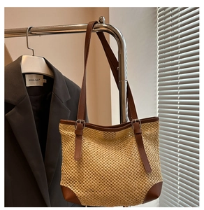 Straw tote bag detail with brown leather strap and adjustable metal buckle on hanger