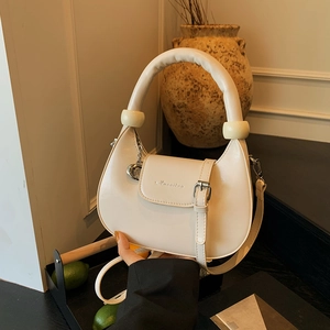 Chic cream half-moon handbag with oversized sphere accents and heart charm on steps