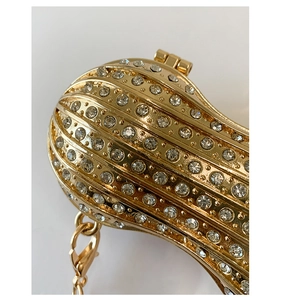 Vista macro della borsa da sera dorata a forma di arachide con strass e catenina