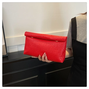 Detail of red woven clutch bag with gold metal ring buckle and fine texture detail