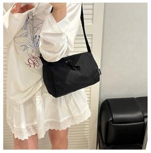 Detail of adjustable strap and white brand label on a black nylon crossbody tote bag