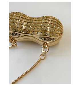 Vista macro della pochette da sera dorata a forma di arachide con strass e catena