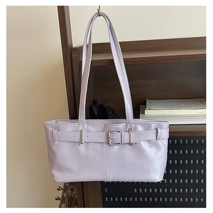 Close-up of light purple leather shoulder bag with decorative belt and silver metal buckle