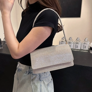 Détail d'une pochette enveloppe argentée à paillettes avec fine bandoulière sur mannequin