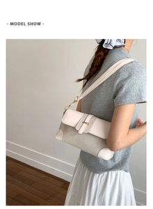 Detail show of cream leather and woven fabric shoulder bag worn by model on white wall