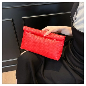 Detail view of red woven leather clutch with gold metal clasp and classic texture