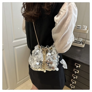 Detailed close-up of a silver sequin bucket bag featuring a gold chain and pearl tassel