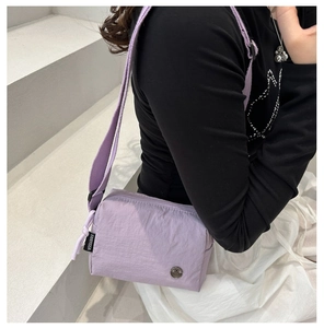 Detail of light purple pleated crossbody bag showing FANYISSA label and M logo