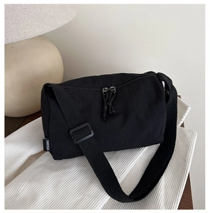 Detail of black nylon crossbody bag featuring textured fabric and adjustable strap buckles