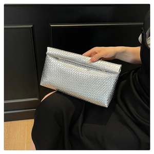 Detail of silver metallic woven clutch bag with elegant flap design and luxury texture