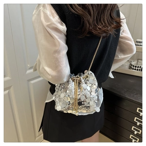 Detail of silver sequin bucket bag with gold chain strap and pearl drawstring tassels
