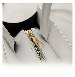 Detail view of high-quality smooth golden metal zipper on white leather handbag