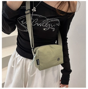 Close-up of a green waterproof nylon crossbody bag with adjustable grey strap for sports