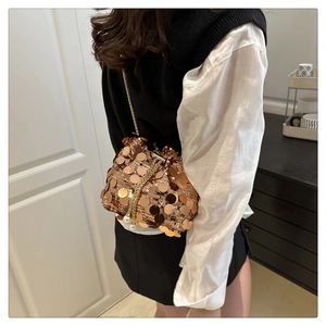 Detail of rose gold sequin bucket bag featuring gold chain and pearl drawstring charms