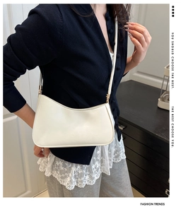 Détail du sac à bandoulière blanc avec ferrures dorées et design élégant en demi-lune