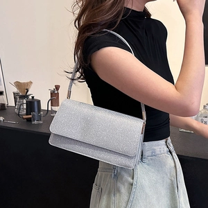 Pochette enveloppe à paillettes argentées avec bandoulière dans un café chic