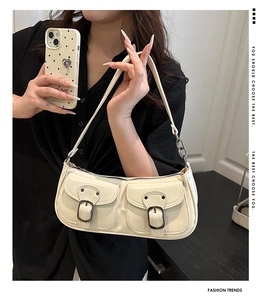 Detail of off-white shoulder bag with vintage metal buckles and dual front pockets