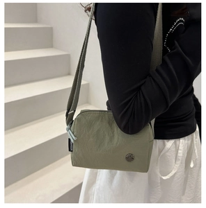 Olive green nylon crossbody bag detail with adjustable strap and metal M logo accent