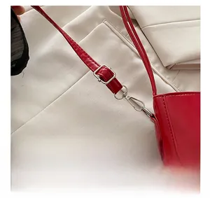 Detail of silver-tone hardware buckle and adjustable strap on red glossy handbag