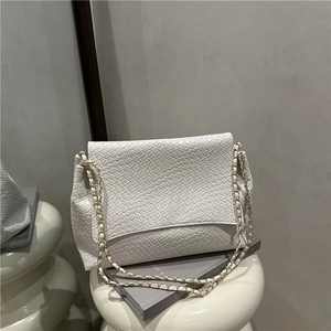 White woven texture flap shoulder bag with gold chain strap on minimalist background