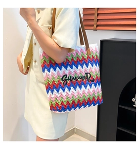 Detail of colorful woven tote bag with summer embroidery and brown leather straps