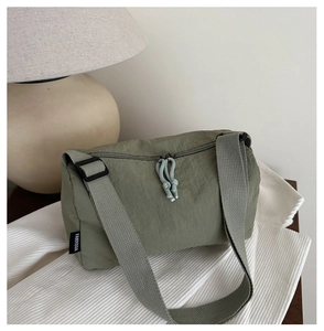 Macro detail of olive green nylon tote bag showing double zippers and brand label