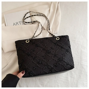 Detail of black quilted tote bag with shimmering sequins and leather chain strap