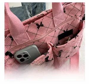 Detail of pink corduroy tote bag showing front pockets storing a smartphone