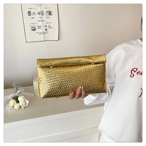 Close-up of golden woven clutch bag featuring intricate criss-cross leather texture
