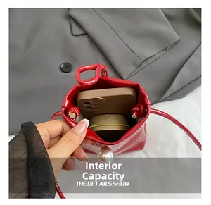 Internal capacity of red patent leather mini crossbody bag with large pearl detail